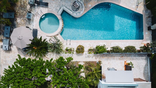 Vista aerea di una zona piscina con vasca idromassaggio, lettini e ombrelloni.