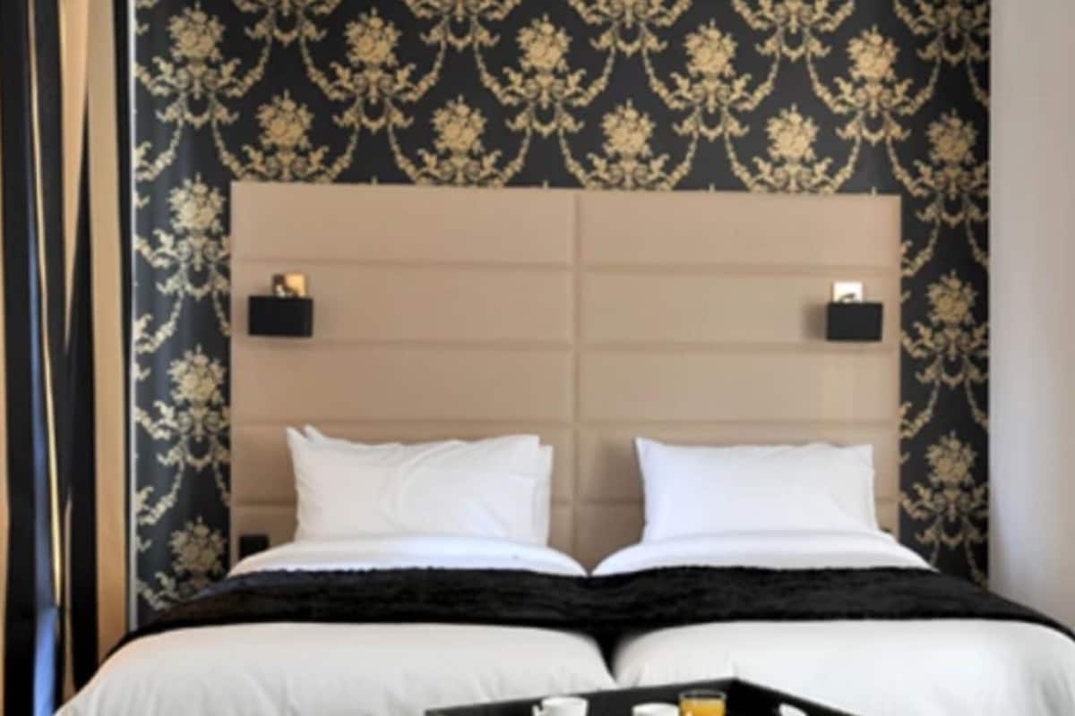 Una cama doble con cabecera, dos mesitas de noche, un adorno en la pared y una silla.