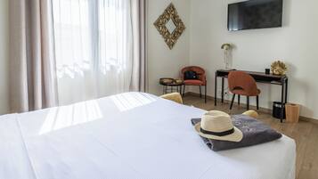 Une chambre d’hôtel équipée d’un lit, d’un bureau, d’une chaise, d’une télévision et d’une fenêtre avec des rideaux.