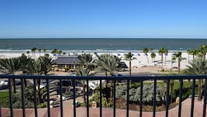 Strandblick mit Palmen, einem Gebäude mit geneigtem Dach und blauem Himmel.