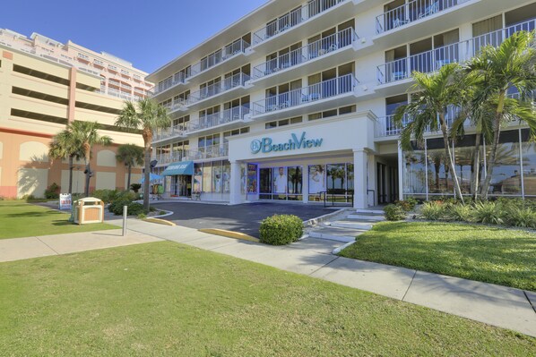 Un hotel de varios pisos con un letrero 'BeachView', asientos exteriores y palmeras.
