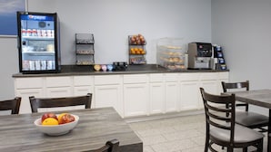 Eine Küchenzeile mit Kühlschrank, Kaffeemaschine und Regalen mit Snacks und Getränken.