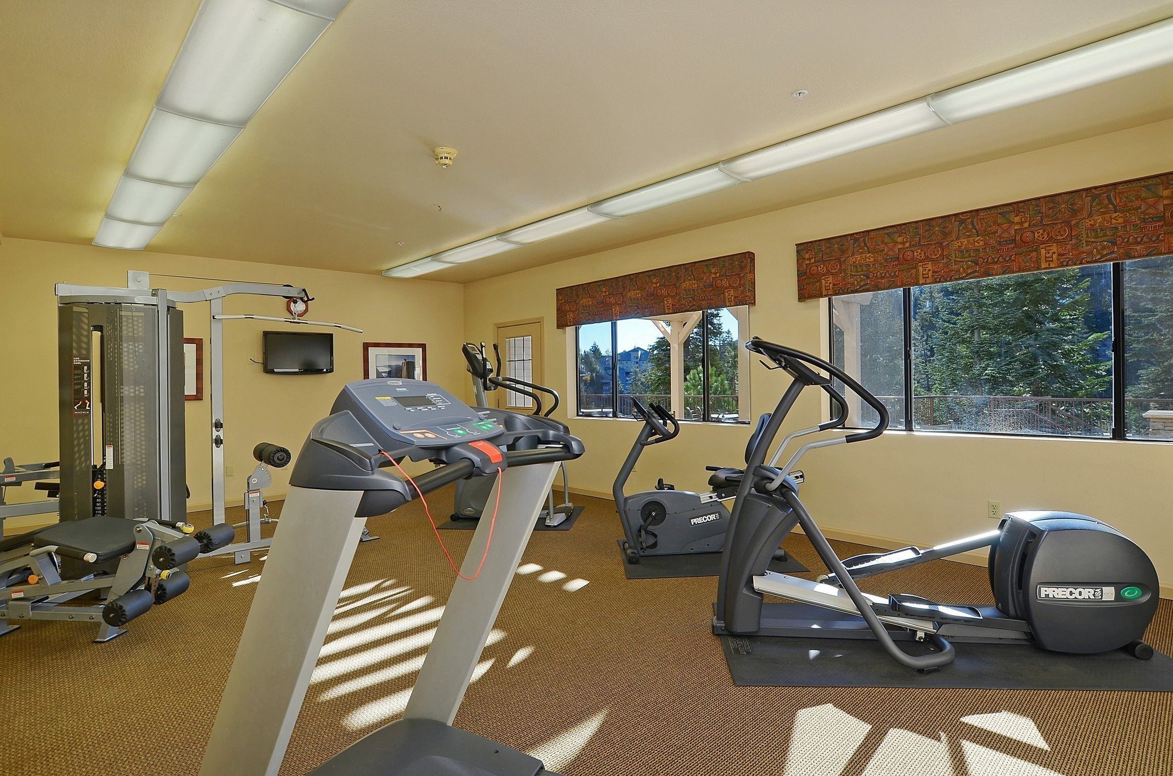 Un gimnasio con cintas de correr, elípticas y equipo de pesas.