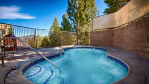 A hot tub with a tiled edge, surrounded by a brick wall and a metal fence. - Ridge Pointe (Stateline)
