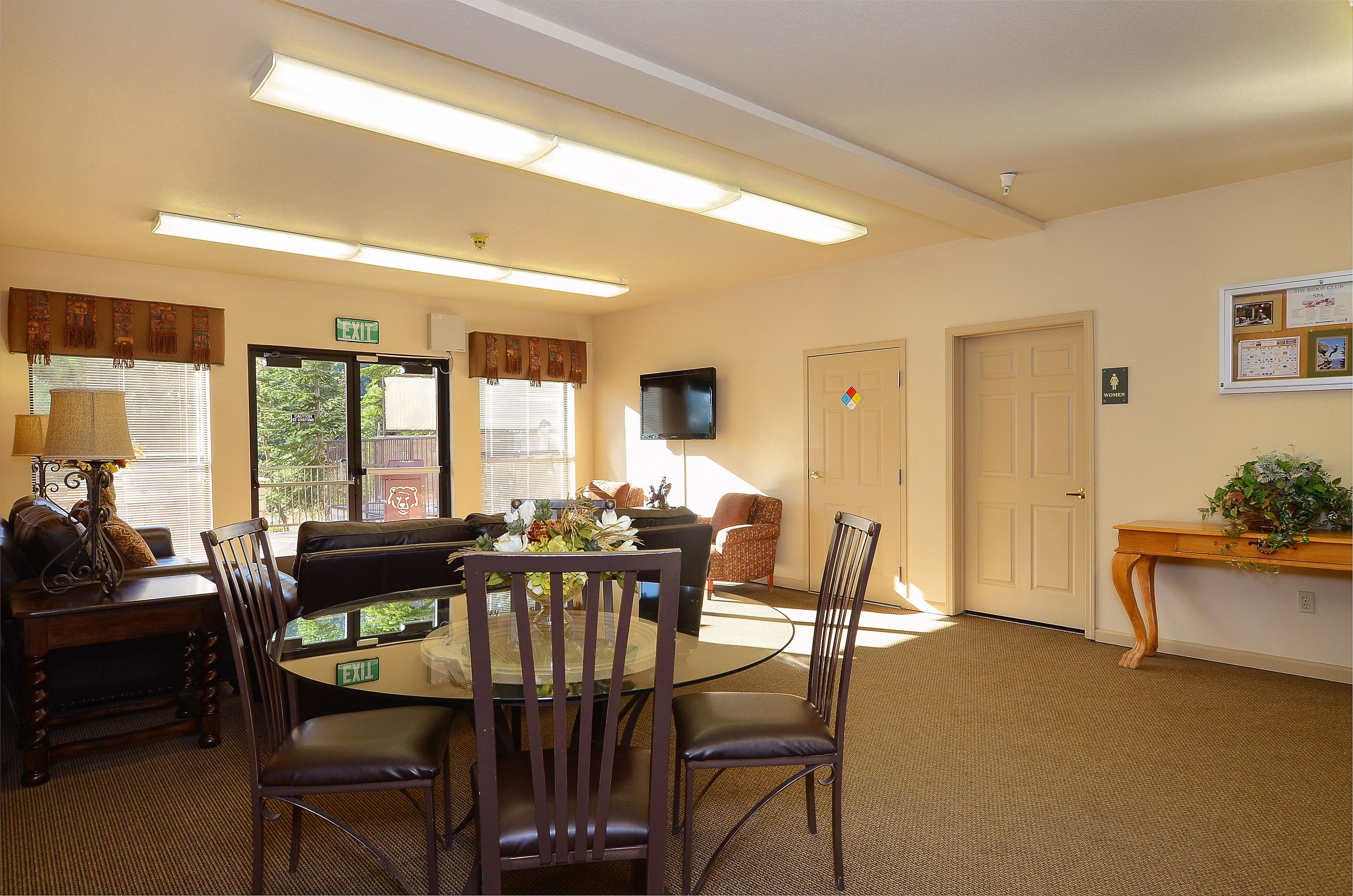 A hotel room with a dining area, a television, and a bulletin board.