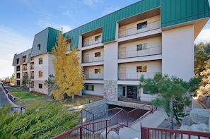 A multi-story residential building with balconies, a stone facade, and a green roof.