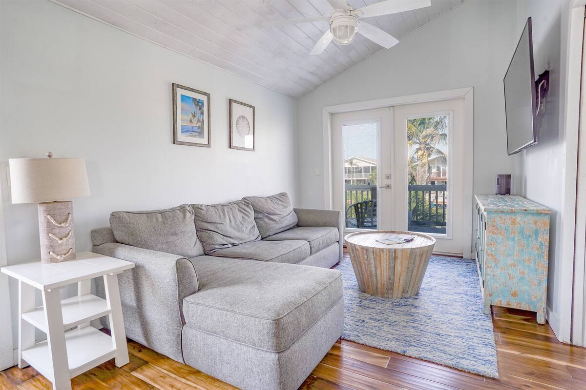 A living room with a grey sofa, a white side table, a round coffee table, and a blue cabinet.