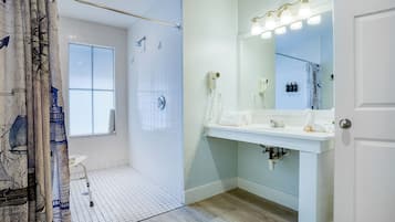 Un baño moderno con ducha, tocador con espejo y ventana.