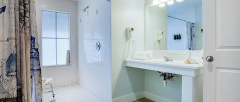 Une salle de bain moderne avec une douche, un meuble-lavabo avec un miroir et une fenêtre.