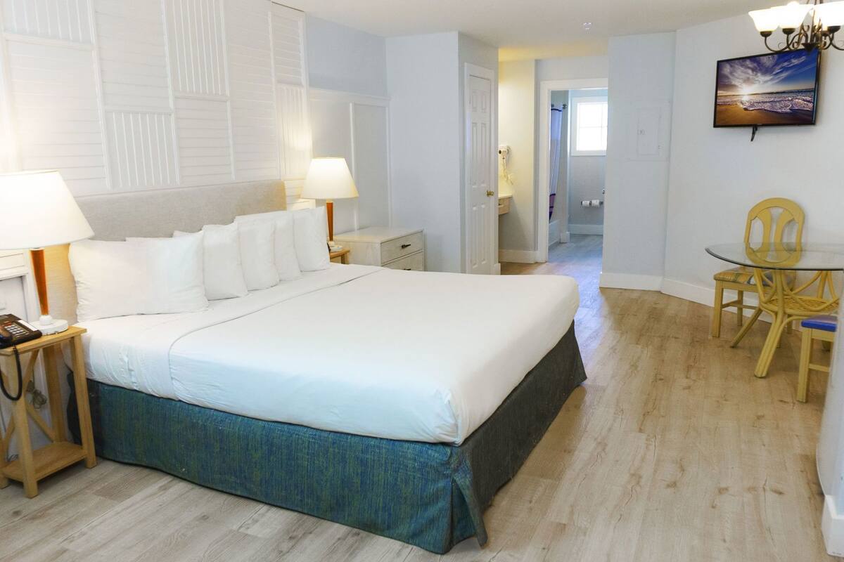 A bedroom with a large bed, bedside lamps, a telephone, and a desk with a chair.
