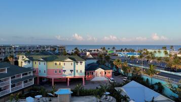 A multi-story hotel with balconies, a pool area, and a view of the beach and ocean.