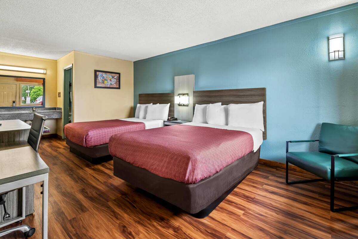 Ein Hotelzimmer mit zwei Betten, einem Schreibtisch und einem Stuhl.