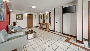 A spacious lobby with a modern design, featuring a seating area with sofas, a coffee table, and a TV mounted on the wall. - Econo Lodge Charlotte Airport Area (Charlotte)