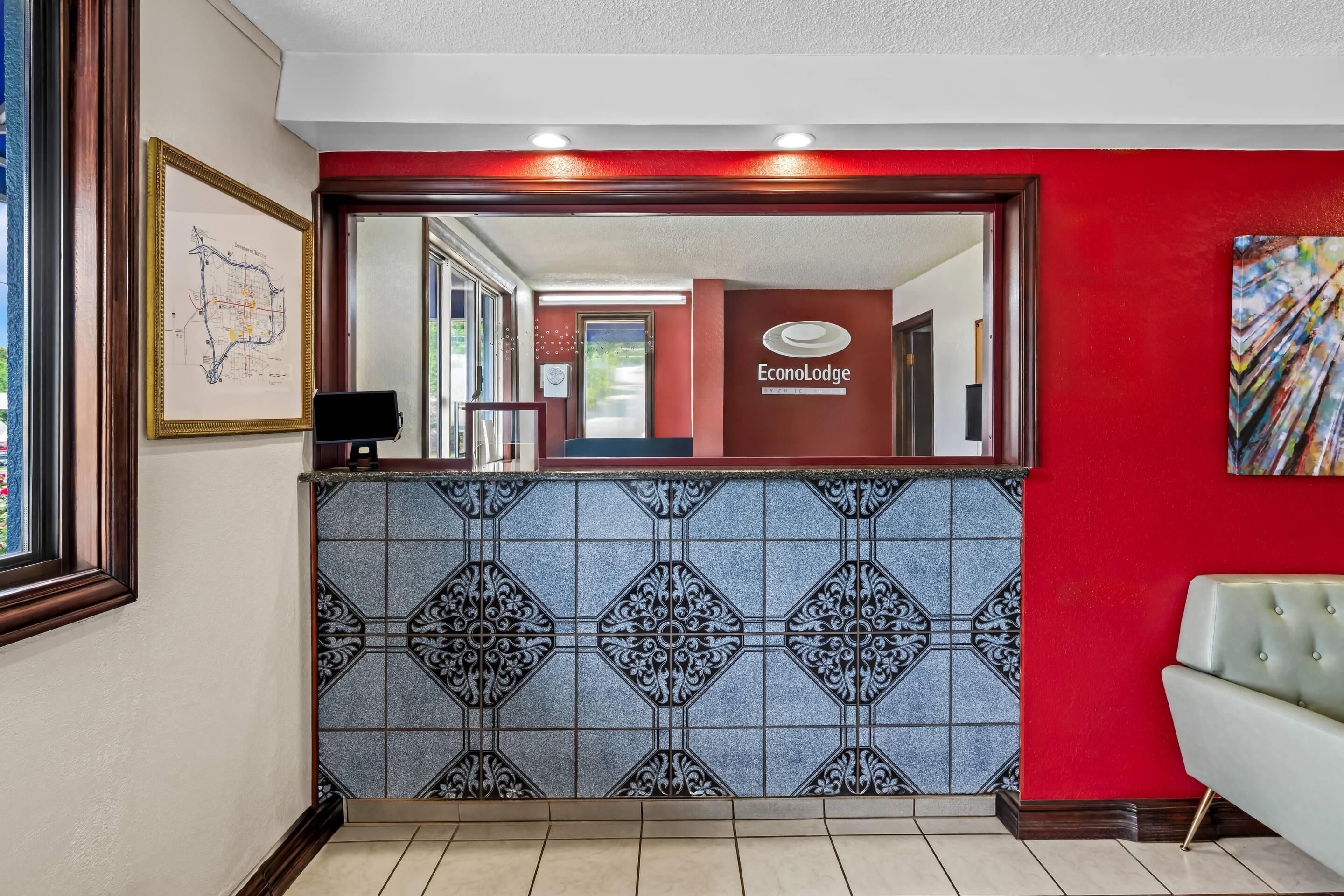 Una zona de recepción con pared de azulejos, un mapa enmarcado y un cartel de EconoLodge.