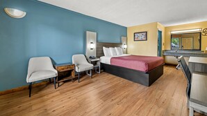 A hotel room with a bed, two chairs, a desk, and a mirror. - Econo Lodge Charlotte Airport Area (Charlotte)