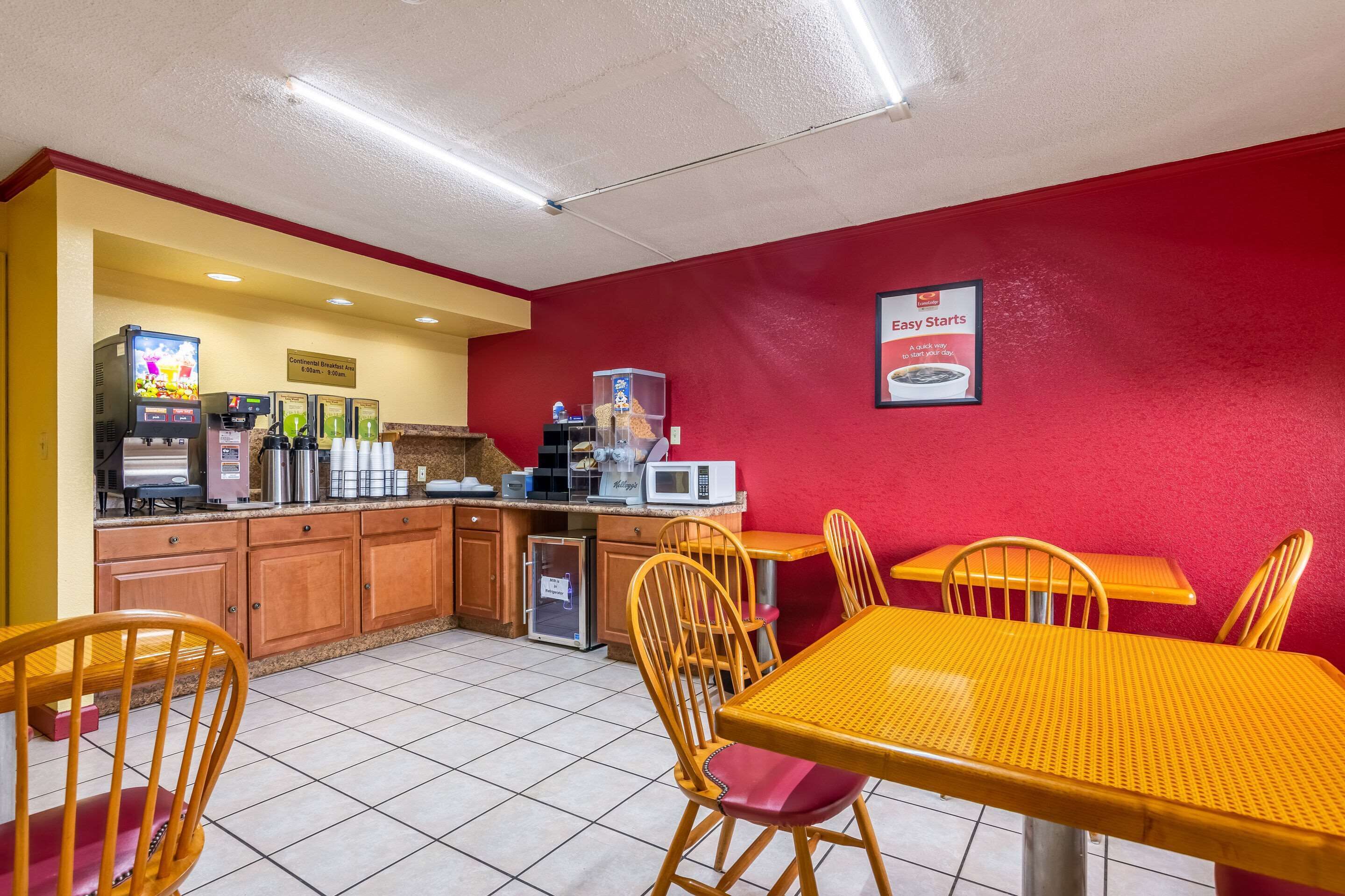 A small, brightly colored restaurant with yellow and red walls, a tiled floor, and wooden furniture.