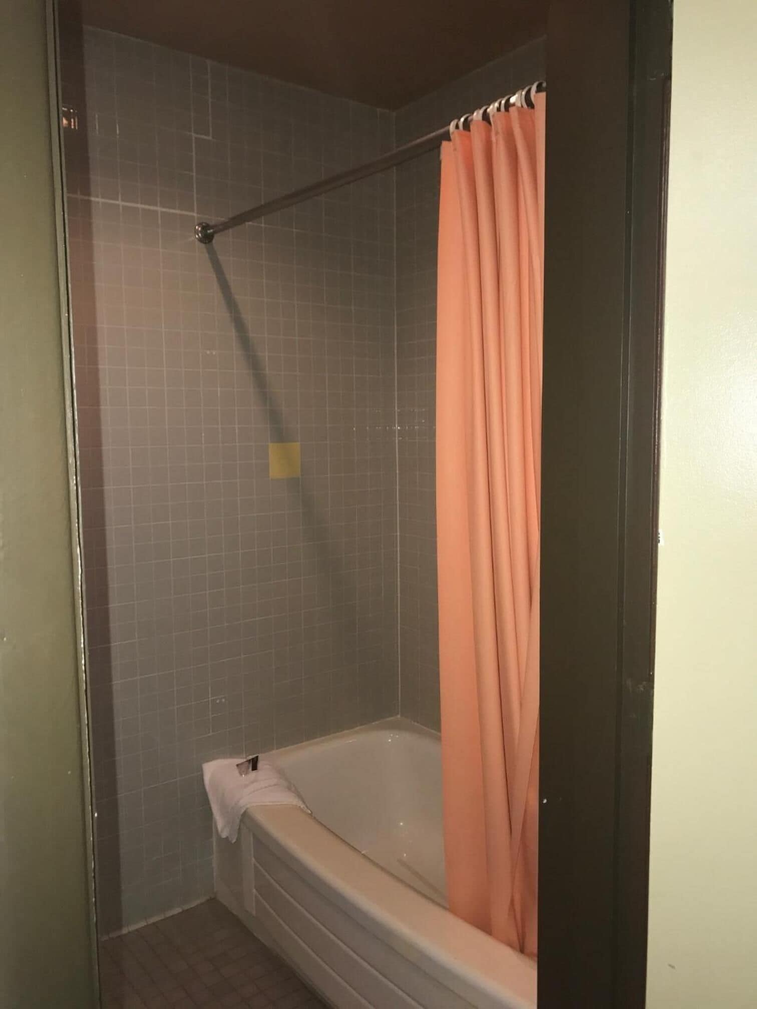 A bathroom with a bathtub, a shower curtain, and tiled walls.