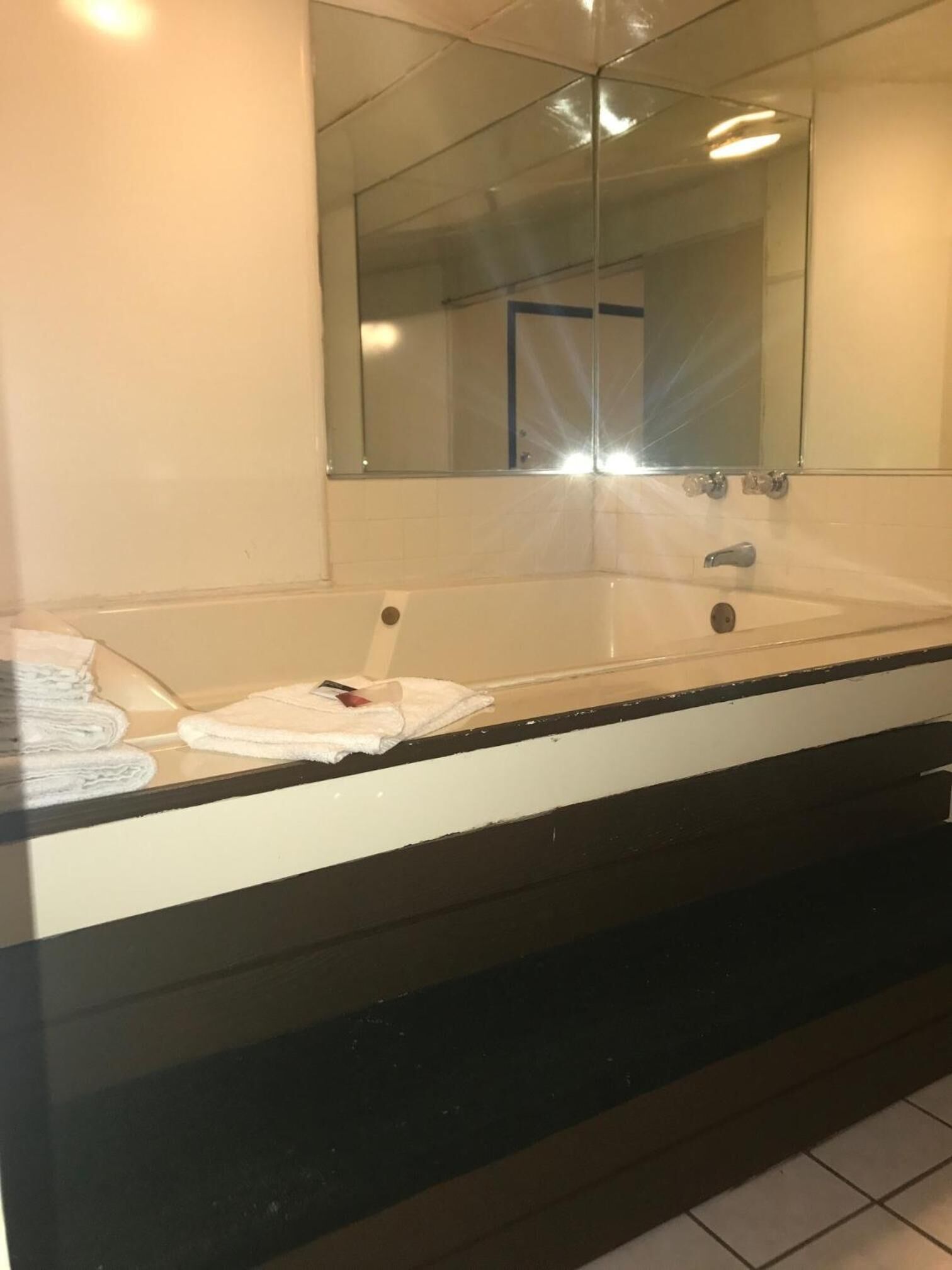 A bathroom with a large bathtub, a mirror above it, and a towel rack with folded towels.