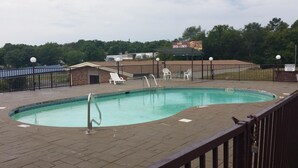 A swimming pool with a fenced deck, lounge chairs, and a lifeguard stand. - Red Carpet Inn (Hot Springs)