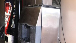 A stainless steel refrigerator with a water dispenser and a Coca-Cola vending machine next to it. - Red Carpet Inn (Hot Springs)