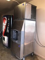 Frigorifero in acciaio inox con erogatore d'acqua e distributore automatico di Coca-Cola adiacente.
