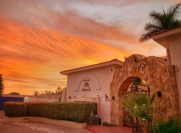 L’entrée d’un hôtel, avec une arche en pierre sur laquelle on peut lire « SANTA FE HOTEL » et une enseigne au-dessus.