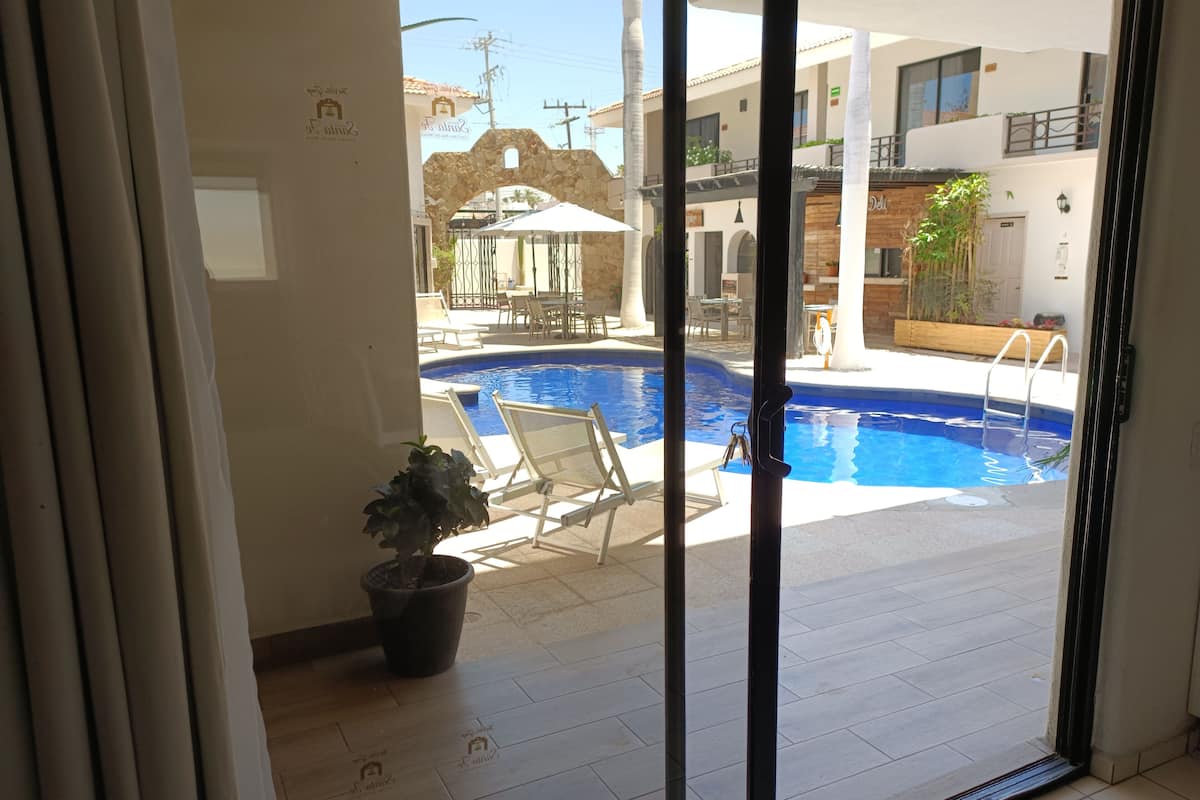A view of a swimming pool with lounge chairs and a stone archway.