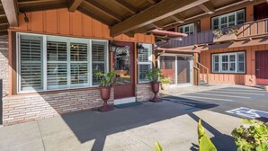 A building with a brick facade, large windows, and a covered entrance area with potted plants. - Clarion Collection Wilkie's Inn Pacific Grove - Monterey (Pacific Grove)