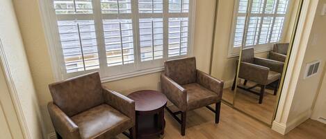 A room with two brown leather armchairs, a small round table, and a large mirror reflecting the room.