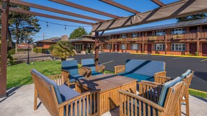 An outdoor seating area with wooden furniture and a covered patio. - Clarion Collection Wilkie's Inn Pacific Grove - Monterey (Pacific Grove)