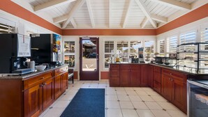 A spacious kitchen with wooden cabinets, a built-in oven, and a coffee station. - Clarion Collection Wilkie's Inn Pacific Grove - Monterey (Pacific Grove)