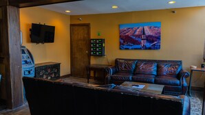 A lobby with a leather sofa, a television mounted on the wall, a painting, and a security control panel. - The Black Bear Lodge at Stratton Mountain Resort (Stratton)
