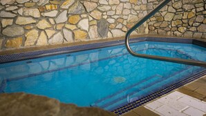 A stone wall surrounding a swimming pool with a metal handrail. - The Black Bear Lodge at Stratton Mountain Resort (Stratton)