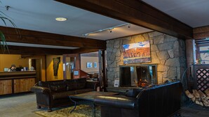 A lobby with a stone fireplace, leather sofas, and a reception desk. - The Black Bear Lodge at Stratton Mountain Resort (Stratton)