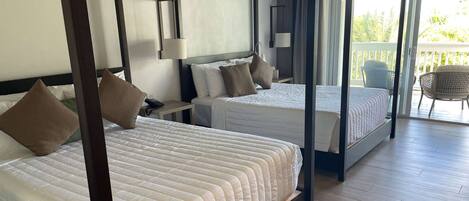 A four-poster bed with a canopy, two bedside tables, and a view of the balcony.