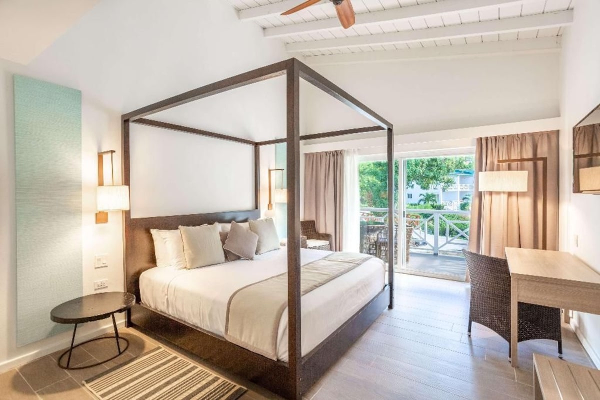 Ein Himmelbett mit Blick auf einen Balkon und eine Außenanlage.