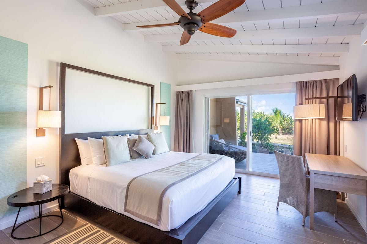 Une chambre d’hôtel avec un grand lit, un bureau et un ventilateur de plafond.