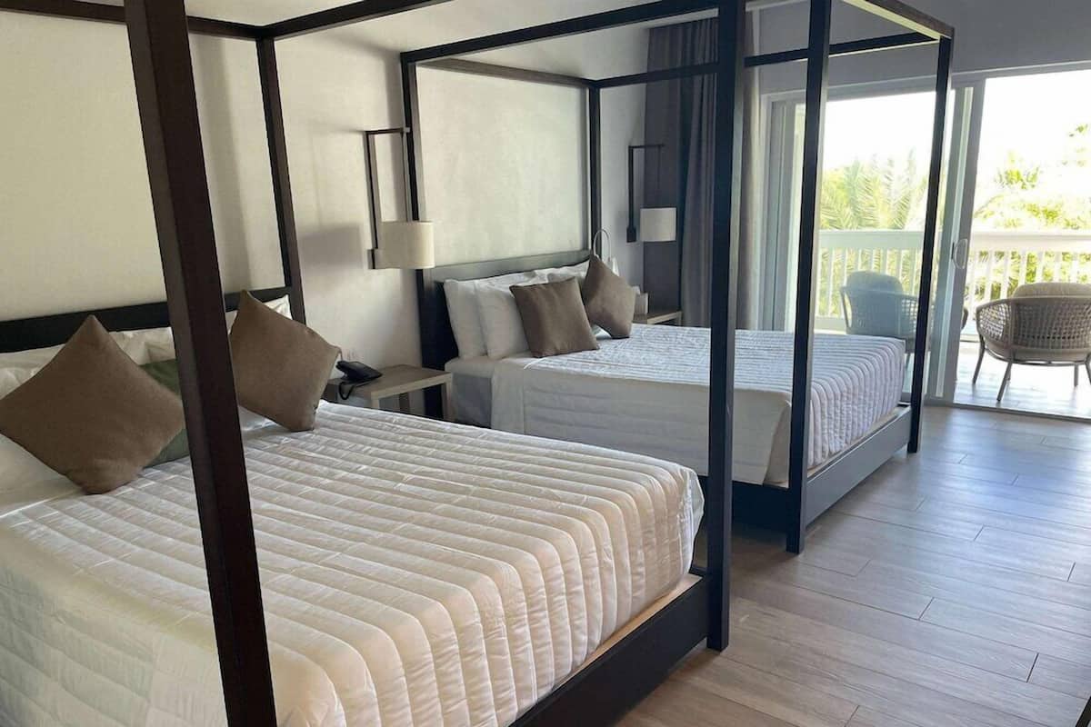 Une chambre avec deux lits, un balcon et une vue sur la verdure.