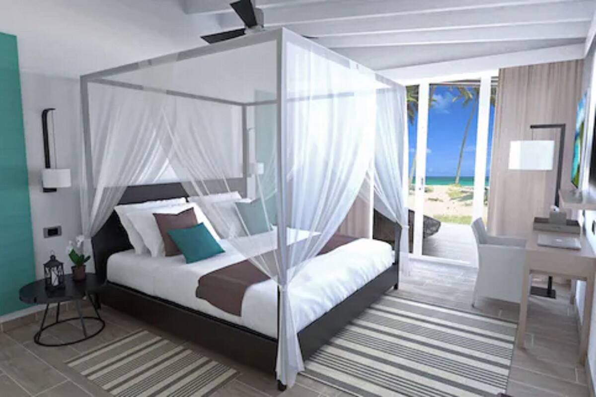 Un lit à baldaquin, un bureau et une vue sur la plage.