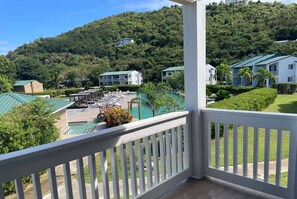 Un hôtel doté d’une piscine, offrant une vue sur une colline verdoyante et agrémenté d’une balustrade blanche.
