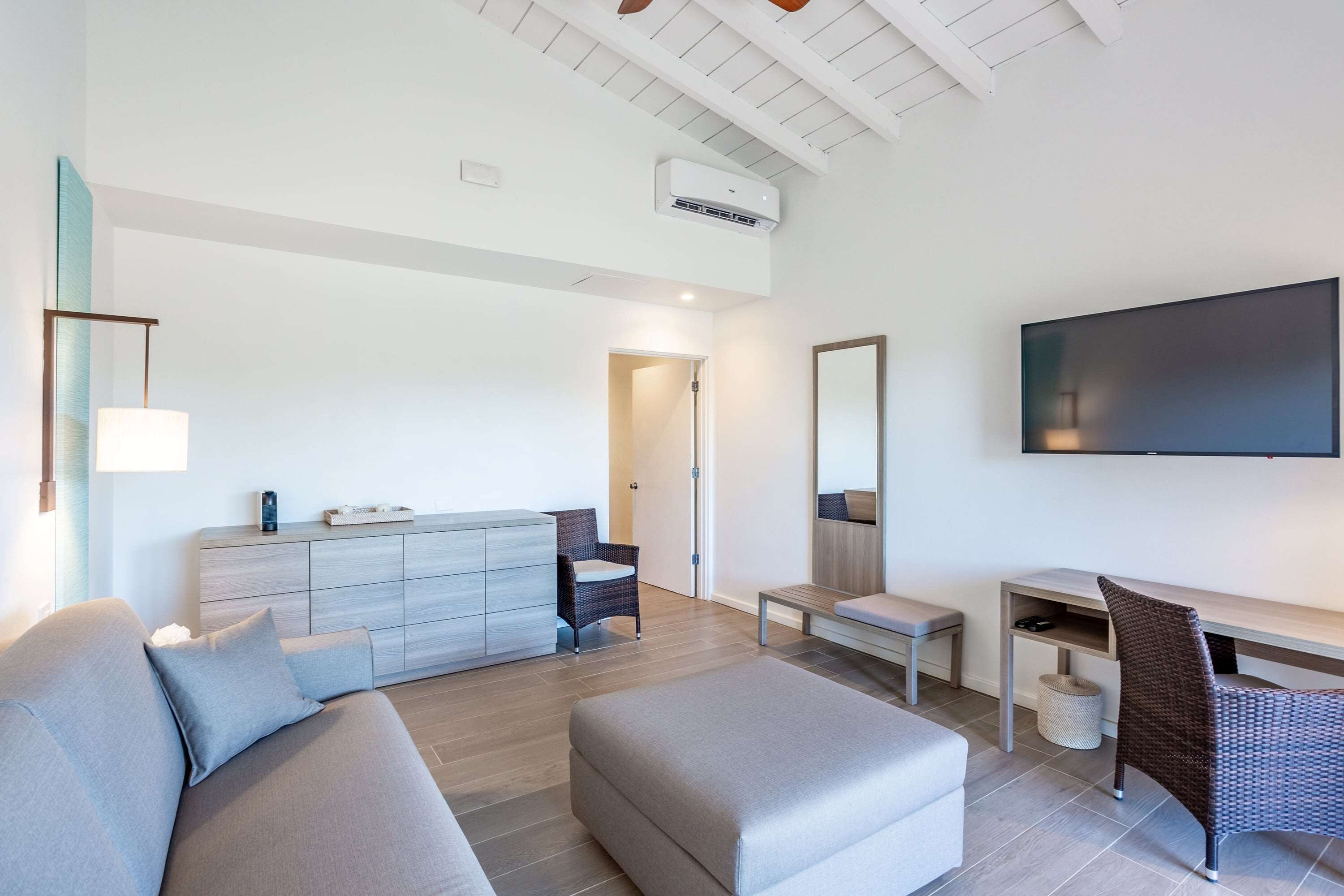 A modern living room with a sofa, ottoman, and a dining area with a table and chairs.