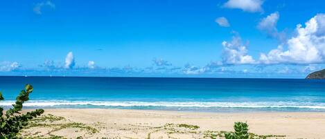 A beach with clear blue water and a sandy shore.