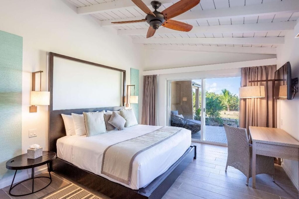 Ein Hotelzimmer mit Bett, Schreibtisch, Deckenventilator und Blick ins Freie.