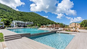 Une piscine à l’eau claire, entourée de chaises longues et d’une terrasse en bois.