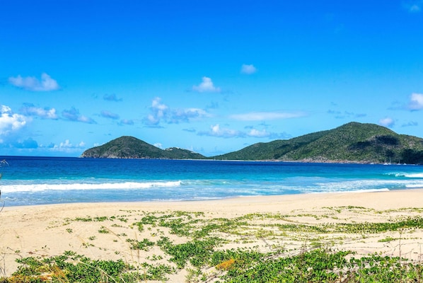 Na praia, areia branca, espreguiçadeiras, toalhas de praia 