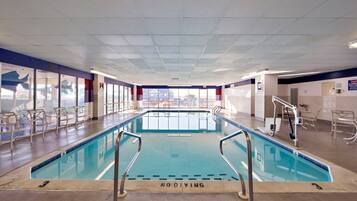 En indendørs swimmingpool med klart vand, et skilt med 'No Diving', og udsigt til det fri gennem store vinduer.