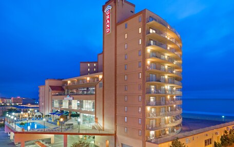 A multi-story hotel with a pool area, balconies, and a view of the ocean.