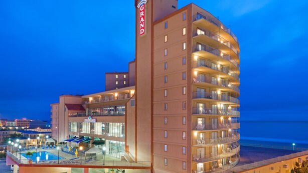 Un hotel de varios pisos con zona de piscina, balcones y vistas al océano.