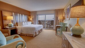 Habitación de hotel con una cama grande, dos sillas, un escritorio y vistas a la ciudad desde la ventana.