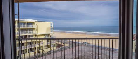 A balcony with a view of a beach and a yellow building.